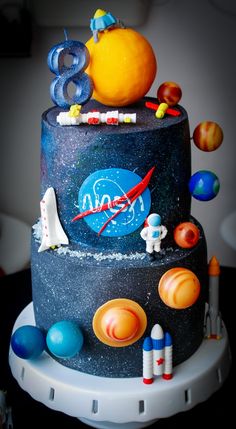 a space themed birthday cake with planets and rockets on the top, including an orange