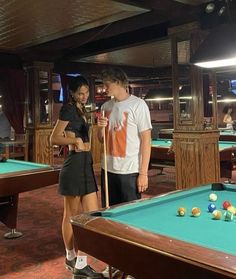 a man and woman standing next to pool tables