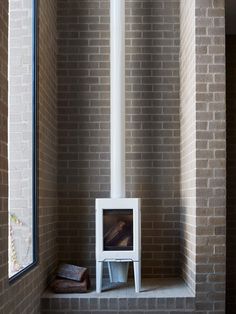 a room with brick walls and a white fireplace in the corner next to a window