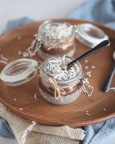 three jars with food in them on a wooden tray