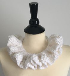 a white crocheted scarf is on a mannequin headdress with a black top