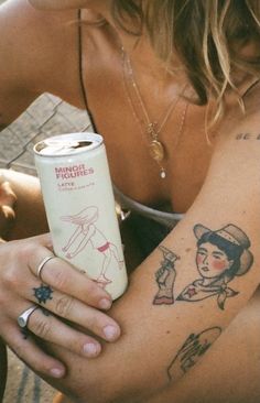 a woman with tattoos on her arm holding a can