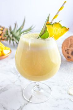 a pineapple drink in a wine glass on a marble table