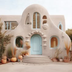 a house made out of cement with blue doors and windows on the outside, surrounded by potted plants