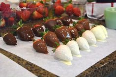 chocolate covered strawberries are lined up on a table