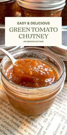 a jar filled with green tomato chutney on top of an open recipe book