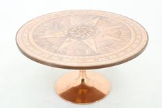 a table that has a compass on it and is sitting on a white surface with no one around it