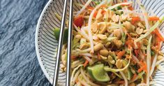 a white bowl filled with salad and chopsticks on top of a blue table cloth