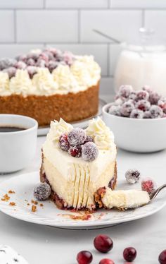 a slice of cheesecake on a plate with berries and cranberries around it