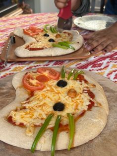 two pizzas with cheese and tomatoes on them