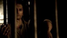 a man standing behind bars in the dark