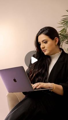 a woman sitting on a couch with a laptop computer in her lap and looking at the screen