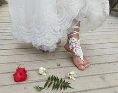 a woman in white dress walking across a bridge with flowers on the ground next to her