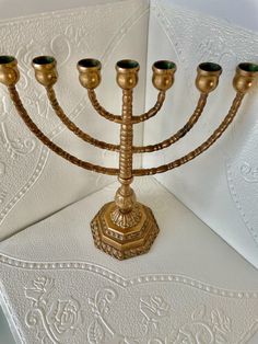 a golden menorah with five candles in it on top of a white table cloth