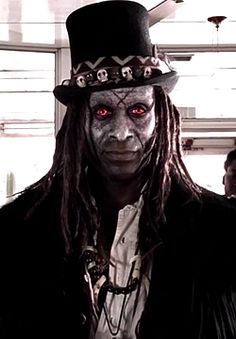 a man with long hair wearing a top hat and dreadlocks on his face