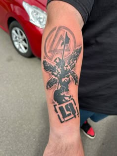 a man with a tattoo on his arm holding a red car in front of him