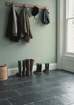 an empty room with several coats hanging on the wall and boots lined up against the wall