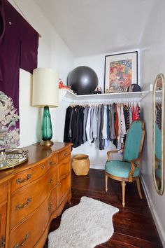 a room with a dresser, chair and hanging items