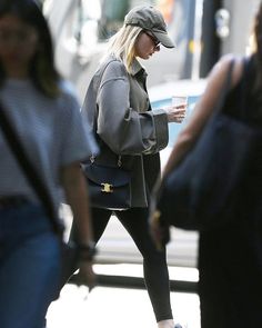 a woman is walking down the street while looking at her cell phone and holding a purse