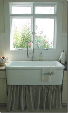 a white kitchen sink sitting under a window