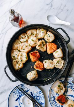 a pan filled with cooked scallops on top of blue and white plates next to utensils