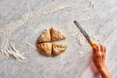 a person is cutting pastries with a knife on a table next to powdered sugar