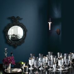 there are many glasses on the table in front of the mirror and wall sconces