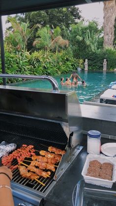 people are swimming in the pool while grilling food