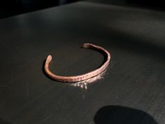 a close up of a piece of metal on a table with a shadow behind it