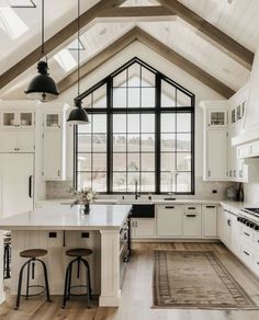 a large kitchen with white cabinets and black accents on the ceiling, along with two stools