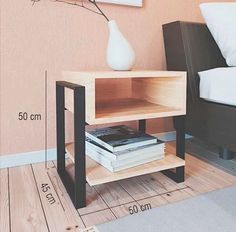 a small wooden table with a book on it next to a bed and a vase