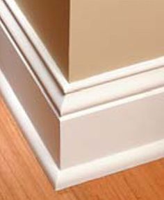 the corner of a room with wood floors and white trim