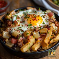 a bowl filled with fries and an egg on top of it, sitting on a wooden table