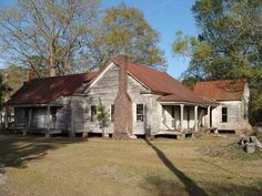 an old run down house sitting in the middle of a field with trees around it