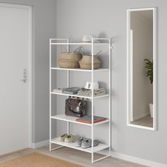 a white shelving unit with baskets and purses on the top shelf next to a mirror