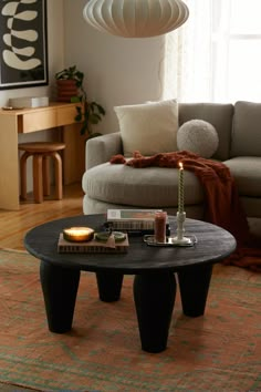 a living room filled with furniture and a table in front of a window on top of a rug