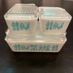 two glass dishes sitting on top of a wooden table next to an empty container with blue designs