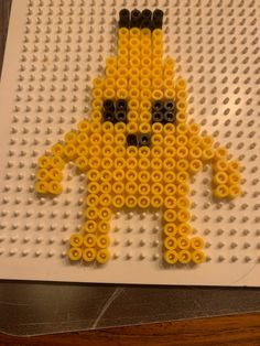 a lego character made out of yellow and black beads on a white board with grey dots