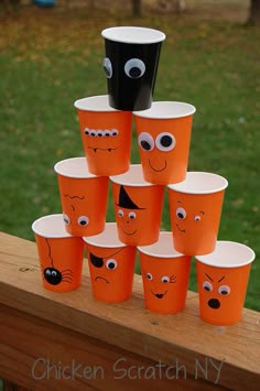 there are many cups with faces on them sitting on a table in front of the grass