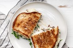 a grilled cheese sandwich on a white plate with a striped napkin next to it