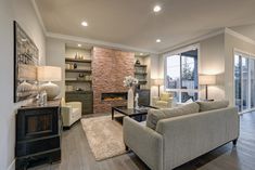 a living room with two couches and a fireplace in the center, surrounded by large windows