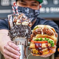 a man holding up a giant burger and ice cream sundae