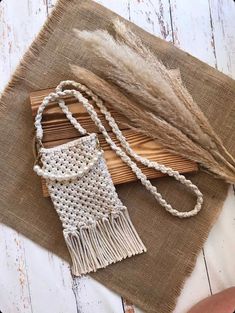 a white beaded bag sitting on top of a wooden table next to some grass