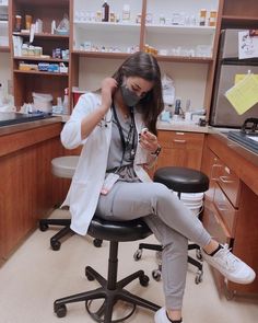 a woman sitting on top of a black chair in a lab wearing a face mask