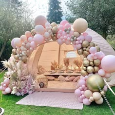 a tent set up with pink and gold balloons