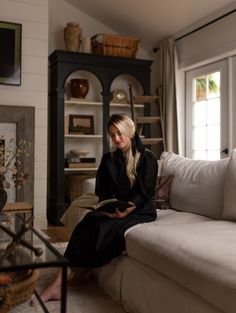 a woman sitting on a couch reading a book