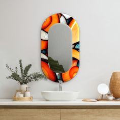 a bathroom sink sitting under a mirror next to a vase and potted green plant