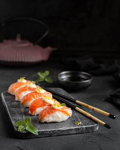 sushi on a black plate with chopsticks next to it