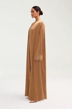 Introducing the Lyana Crystal Mesh Satin Abaya in Champagne. This luxurious abaya features exquisite crystal mesh detailing on the sleeves, adding a touch of sophistication to any outfit. Made with high-quality satin, this abaya exudes luxury and exclusivity. Elevate your wardrobe with this must-have piece. Model is 5'7" and is wearing size XS/58". Luxurious Abaya, Satin Abaya, White Dress Formal, Nikkah Dress, Dresses Flowy, Hijab Pins, Engagement Dresses, Kids Outerwear, Dress Satin