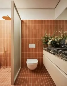 a bathroom with tiled walls and brown flooring